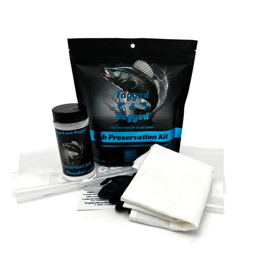A fish preservation kit, including a black plastic bag with a fish graphic, 2 clear preservation bags, preservation powder, gloves, and a white towel laid out in front.