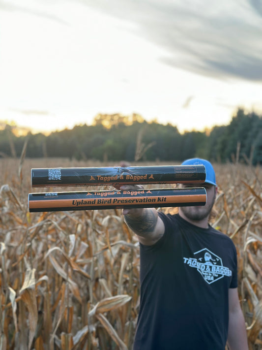 Jonny holding Tagged and Bagged Upland Bird Preservation Kits in cornfield at golden hour