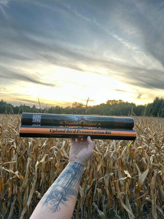 Upland Bird Preservation Kit held up over a cornfield at sunset