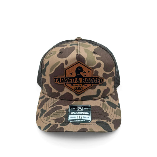 Camouflage baseball cap with 'Tagged & Bagged' logo on a white background